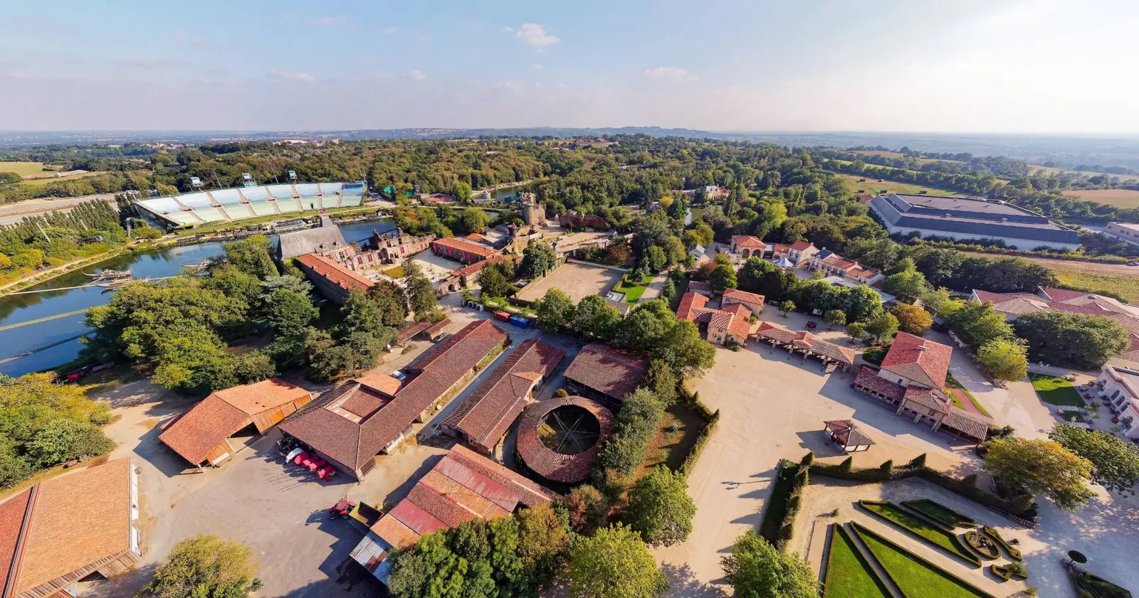 Vue aérienne par drone du Puy du Fou, avec la tribune de la Cinéscénie au bord du lac, le château et les jardins