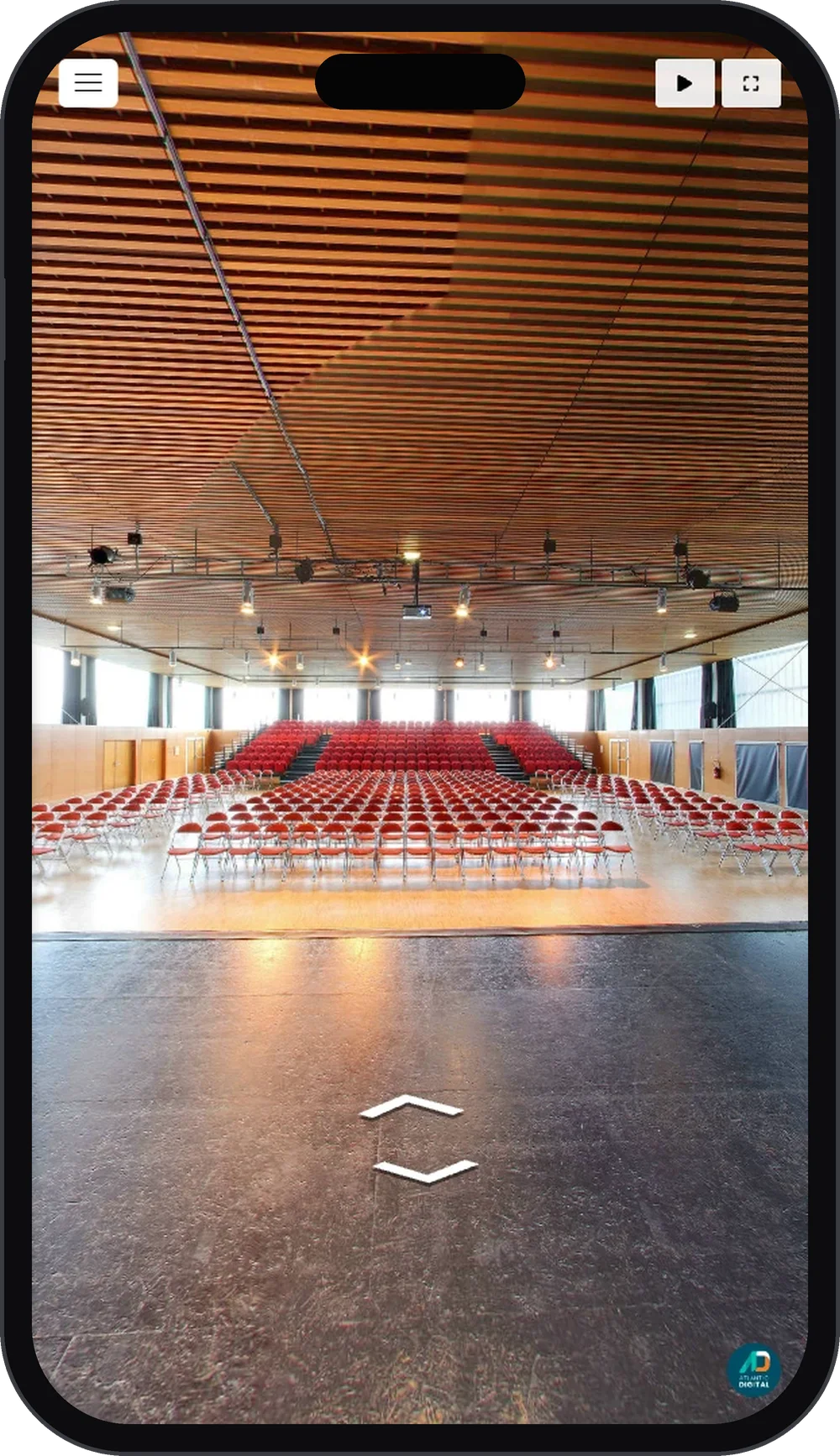 Visite virtuelle 360° de la salle de spectacle du Sabot d'Or à Saint-Gilles affichée sur un smartphone, gradins de fauteuils rouges face à la scène